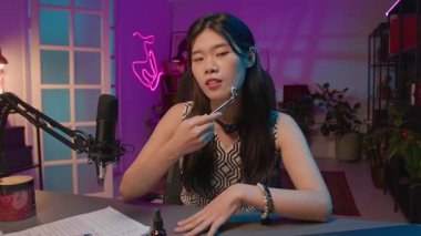 Genç Asyalı kadın güzellik uzmanı, canlı yayında abonelere yeni yüz masajı modelini göstererek cilt sertliği ve ten rengi için faydalarını anlatıyor.