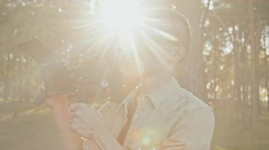 Profesyonel kameramanın belden yukarı çekimi. Sıcak yaz gününde dışarıda çalışıyor. Çekimler için video kamera kuruyor.