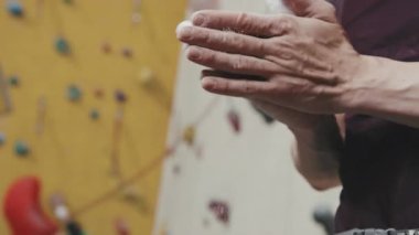 Spor kompleksinde duvarlara tırmanmadan önce tanınmayan erkek ellerinin beyaz tebeşir magnezyum tozuyla ellerini ovmasının yavaş çekimi.