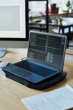 Kodlanmış veriye sahip dizüstü bilgisayar veya yeni yazılım ürünü birlikte çalışma alanındaki modern programcının iş yerinde duruyor