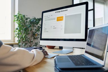 Erkek programcı veya tasarımcının çalışması sırasında dizüstü bilgisayarın yanında duran yapay zeka görüntü oluşturuculu masaüstü bilgisayar ekranı
