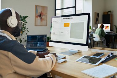 Genç Afro-Amerikalı yazılım geliştirici AI resim oluşturma programını masaüstü bilgisayarı ve dizüstü bilgisayarda test ediyor