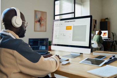 Bilgisayar klavyesinde yazan ve yeni içerik oluştururken yapay zeka görüntü üreticisi kullanan genç işadamının yan görünümü