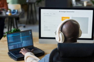 Kulaklıklı genç erkek programcının kel kafasına odaklan. Laptop tuş takımında yazarken iş yerindeki verileri deşifre et.