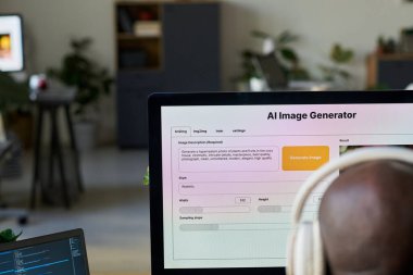 Masaüstü bilgisayarının ekranındaki görüntü jeneratörü kulaklıklı genç Afrikalı Amerikalı erkek tasarımcının önünde duruyor.