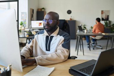 Bilgisayar tuş takımında yazan ve veri çözerken veya yeni içerik oluştururken ekrana bakan ciddi bir erkek programcı