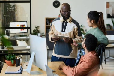 Tabletli genç, ciddi bir erkek programcı. Toplantıda yeni projeyi tartışırken Çinli kadın meslektaşına bakıyor.
