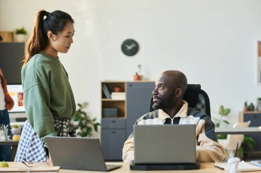 Genç ve ciddi bir erkek çalışan, yeni yazılımın gelişimi ile ilgili detaylar hakkında konuşurken kadın meslektaşına bakıyor.