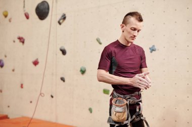 Çağdaş sporcu, duvar tırmanışı eğitiminden önce avuç içlerine pudra sürüyor.