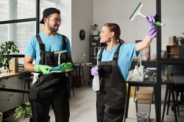 Temizlik işinde çalışırken üniformalı meslektaşlar birbirleriyle konuşuyorlar.