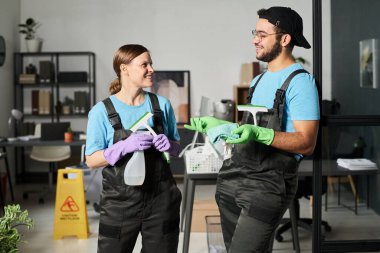 Üniformalı meslektaşlar ofiste dikilirken iş tartışıyorlar.