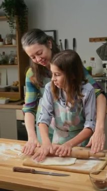 Elmalı turta yemek ve annemle sohbet etmek için masaya yuvarlanan önlüklü beyaz bir çocuğun hafta sonu evde birlikte pasta pişirirken orta boy dikey görüntüsü.