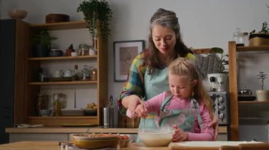 Kafkasyalı annesini severken, mavi önlük giyerken, küçük kızına mutfakta kek yapmasını öğretirken, kasedeki malzemeleri karıştırırken, sonra da onu alnından öperken.