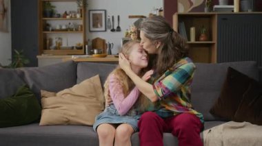 Orta yaşlı, bekar bir anne ve 8 yaşında bir kızın evde kanepede oturup sarılıp, sarılıp, öpüşürken kayıtsız şartsız sevgi ve şefkat gösterdikleri bir fotoğraf.