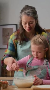Kafkasyalı bir annenin 8 yaşındaki kızını okuttuğu orta boy dikey fotoğraf. Mutfakta kekler için hamur işi yaparken, kasede malzemeleri çırparken, sarılıp öpüşürken, hafta sonunu birlikte geçirirken.