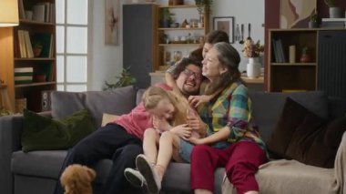 Orta karar beyaz bir koca, uzuvları farklı engelli, sevgili karısı, genç oğlu ve kızı kanepede oturuyor, sarılıyor, gıdıklama oyunu oynuyor, evcil bir köpek gibi zıplayıp duruyor.