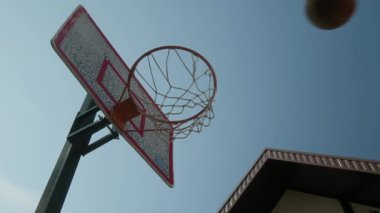 Düşük açılı hiç kimse açık havada aile evinin yanına, mavi gökyüzüne ve amatör oyun ya da antrenman sırasında kaleye fırlatılan basketbola karşı potadan basket oynayamaz.
