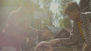 Açık havada babasıyla basketbol oynayan, babası banliyö aile evinin yanında, parlak gün ışığında top sürerken orta boy yavaş çekim yapan Afro-Amerikan çocuk.
