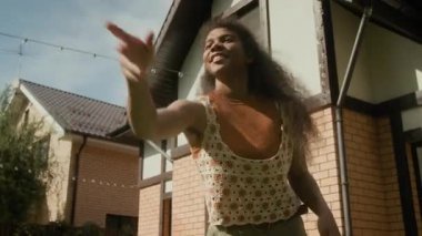 Sıcak bir yaz günü, banliyö evinin yanında arkadaşlarıyla ya da aile üyeleriyle uçan diskle oynayan 14 yaşındaki neşeli Afrikalı Amerikalı kızın orta açı çekimi.
