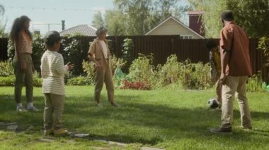 Neşeli, çoklu, beyaz bir aile annesi, Afrikalı bir Amerikalı baba, melez bir kız ve iki oğlan bahçede yeşil çimlerde daireler çizip birlikte eğleniyorlar.