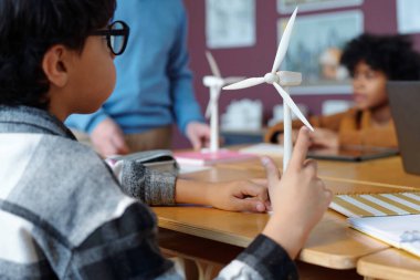 Fen sınıfında rüzgar türbini modellerini kullanarak yenilenebilir enerji kaynakları hakkında pratik eğitim alan okul çocukları, sürdürülebilirlik kavramları konusunda öğretmenlik sunuyorlar.