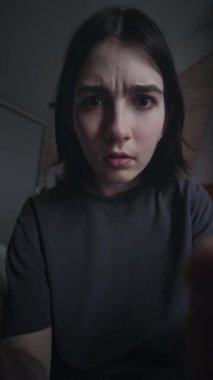 Sosyal medyada akıllı telefondan kayan, siber zorbadan gelen nefret mesajlarını okuyan, çığlık atan, ağlayan ve aletleri fırlatıp atan korkmuş beyaz kızın yüzünün ve ellerinin dikey görüntüsü.