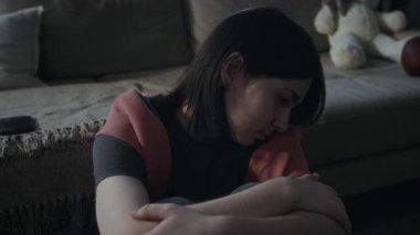 Ağlamaktan gözleri şişmiş, evde tek başına oturan, siber zorbalıktan, ilişki ayrılığından muzdarip, perişan olmuş, Hollandalı bir kızın portresi. Kanepede akıllı telefon.