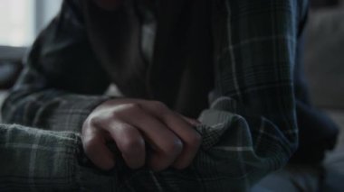 Üzüntülü genç Afrikalı Amerikalı çocuğun ellerinin ve yüzünün yakın çekimleri gömleğinin koluyla oynaşırken aynı zamanda internet trollerinin akıllı telefondaki küçük düşürücü mesajlarını okuyor.