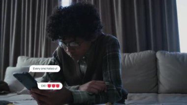 Depresyondaki Afrikalı Amerikalı çocuğun video efektleriyle orta boy bir fotoğraf, inek gözlükleri takıyor, sosyal medyadaki zorbaların şiddet dolu mesajlarına bakıyor, etrafında beliriyor.