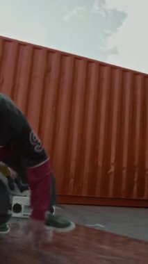 Kenar mahalleli Z-Boy 'un nefes kesici break dans hareketleri yaparken vücudunu döndürdüğü ve dışarıda onu izleyenler arasında pratik yaptığı dikey el kamerası görüntüsü.