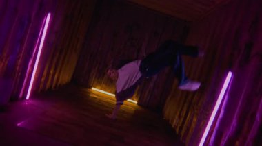 Kafkasyalı gen- z-boy 'un yavaş çekimleri büyük bir beceri ve tutkuyla baş aşağı kaya hareketleri yapıyor, neon ışıkların altında iç mekanları yıkıyor.