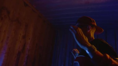 Yan görünüm, havalı, gözlüklü Z-B-Boy 'un el ele dans edip neon ışığın altında hip hop müziğinin keyfini çıkardığı yakın çekim.