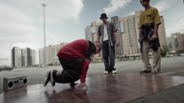 Sokak tarzı giyinmiş yetenekli beyaz çocuk şehir ortamında hip hop müzik eşliğinde arkadaşlarıyla onu neşelendirirken el kamerasıyla çekildi.