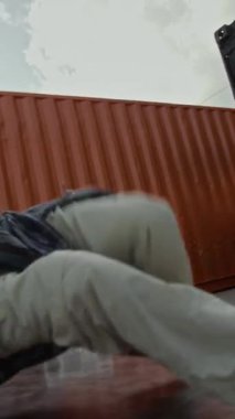 Sokak tarzı giyinmiş, yetenekli beyaz bir B-Boy 'un arkadaşlarının önünde dışarıda nefes kesici break dans hareketleri yaparken çekilmiş dikey bir el resmi.