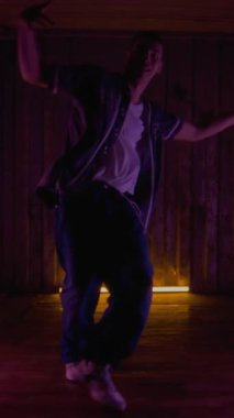 Şehir kıyafetleri içindeki genç beyaz çocuk canlı ışık altında dans ederken rock 'n' roll 'un rock' n 'roll' unu icra ediyor.