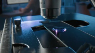 Cam kaydıraktaki sıvı örneklerini incelerken objektif lenslerin konumunu değiştiren bilinmeyen mikroskopların yakın görüntüsü