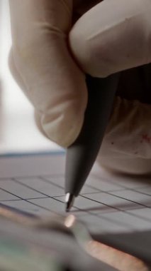 Tıbbi belgeleri doldururken kene izleri koyan tanınmayan bir laboratuvar çalışanının eldivenli elinin dikey yakın görüntüsü