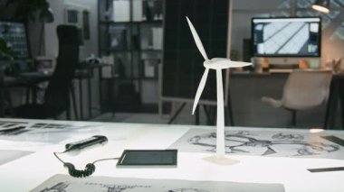 Arka planda güneş paneli prototipi olan yenilenebilir ve sürdürülebilir teknoloji ofisindeki çizimler arasında çizim masasında beyaz rüzgar türbini modeline yakın hiç kimse yok.