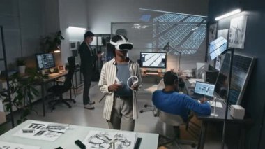 Kadın mucitlerin sanal gerçeklik kulaklıkları ve kontrolörleri kullanarak, modern ofiste yenilenebilir çözümler geliştirerek, güneş panelleri ve rüzgar türbinleri üzerinde çalışan meslektaşlarının görüntülerini çek.