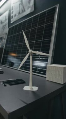 Yenilenebilir enerji ofisindeki güneş paneli prototipinin yakınındaki çalışma masasına yerleştirilmiş küçük rüzgar türbininin dikey görüntüsü yok.