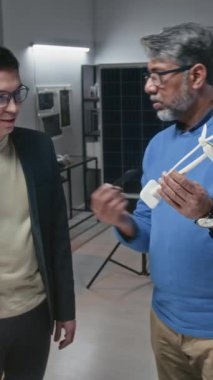 Yetişkin erkek Hintli mühendisin eğitime küçük model kullanarak sürdürülebilir teknolojiler geliştirerek rüzgar türbininin yapısını ve çalışmalarını açıklarken dikey çekimleri.