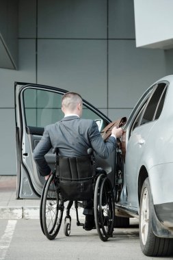 Takım elbiseli, özürlü iş adamının arabasına binerken...