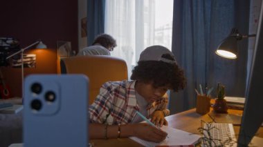 Afro-Amerikalı öğrenci defterine not alıyor, sonra akıllı telefon ekranında yeni bir video oyunu fark ediyor, annesini arıyor ve onunla oynamaya başlıyor.