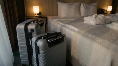 İki modern gümüş bavul otel yatağının yanına katlanmış bornozlar ve havlularla birlikte sıcak ışıklandırmalı misafir odasına yerleştirildi.