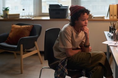 Psikolog ofisinde sandalyede oturan ve danışmanın tavsiyelerini dinleyen sıradan giyinmiş tatlı bir öğrenci.