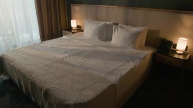 Kadın otel temizlikçisi misafir odasındaki temizlik sırasında temiz havlu getiriyor ve yatak yapıyor.