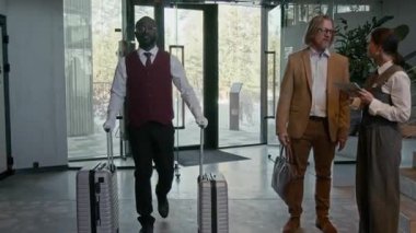 Konuk ve resepsiyonist otel lobisinde ayrıntıları tartışırken Afrika kökenli Amerikalı komi üniformalı iki bavulla yürüyordu.