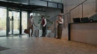 Modern otel lobisine valiz taşıyıcı çocuk olarak girdi. Bavul ve resepsiyonist ona dijital tablet kullanarak yardımcı oldu.