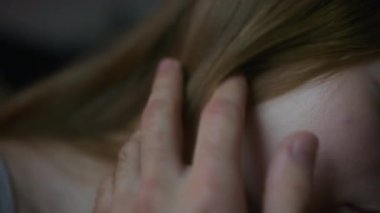 Erkek elinin, genç sevgilisinin açık renk saçlarına dokunup okşadığı, dokunuşlar, yakınlık ve romantizm yoluyla derin duygular ifade ettiği yakın çekim.