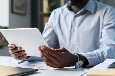 Ofisteki video görüşmesi sırasında elinde dijital tablet tutan tanınmayan siyahi iş adamının elleri